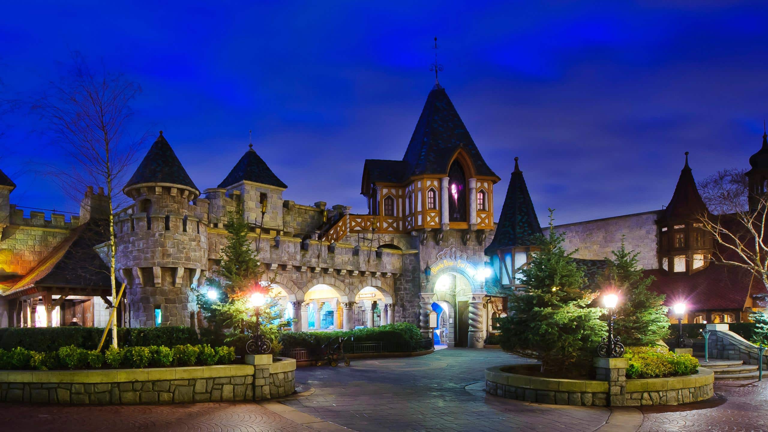 Entrée de l'attraction Blanche Neige et les Sept Nains à Fantasyland, façade de chalet en bois peint avec la méchante sorcière en vitrail