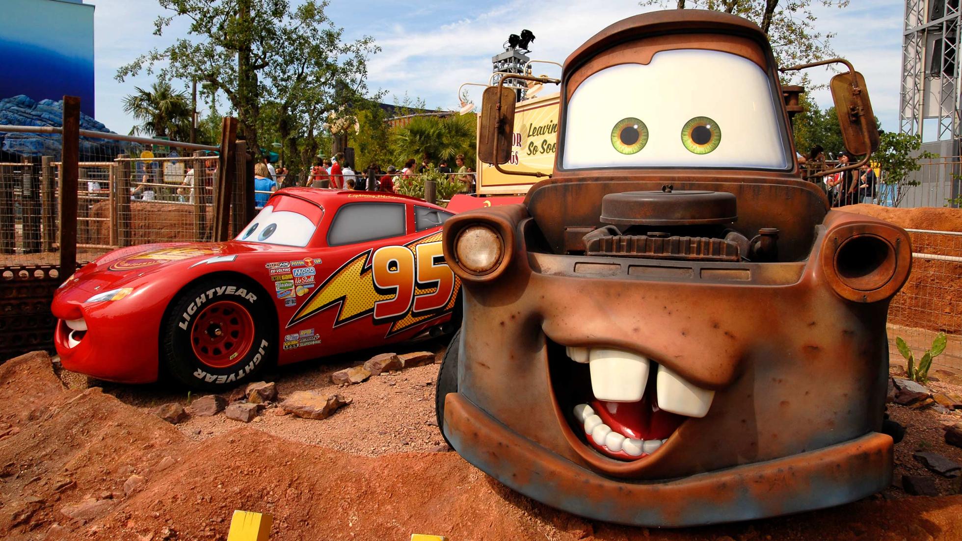 Manège Cars Quatre Roues Rallye dans Worlds of Pixar, voitures colorées inspirées de Radiator Springs sur fond de rochers ocre