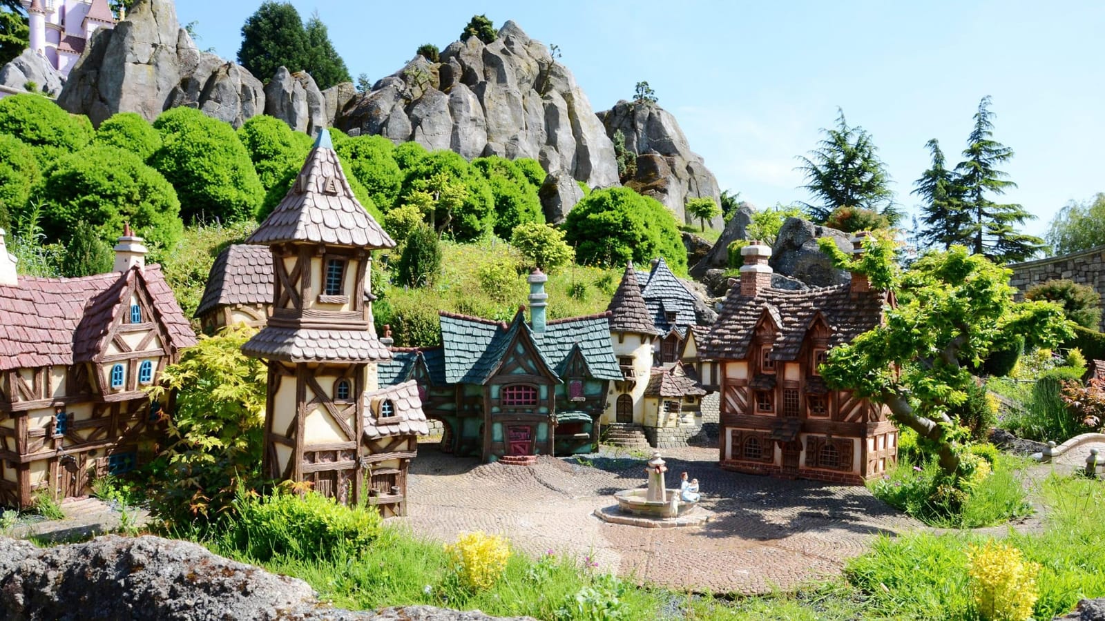 Barques naviguant sur le canal du Pays des Contes de Fées à Fantasyland, entourées de dioramas miniatures représentant des scènes de contes Disney