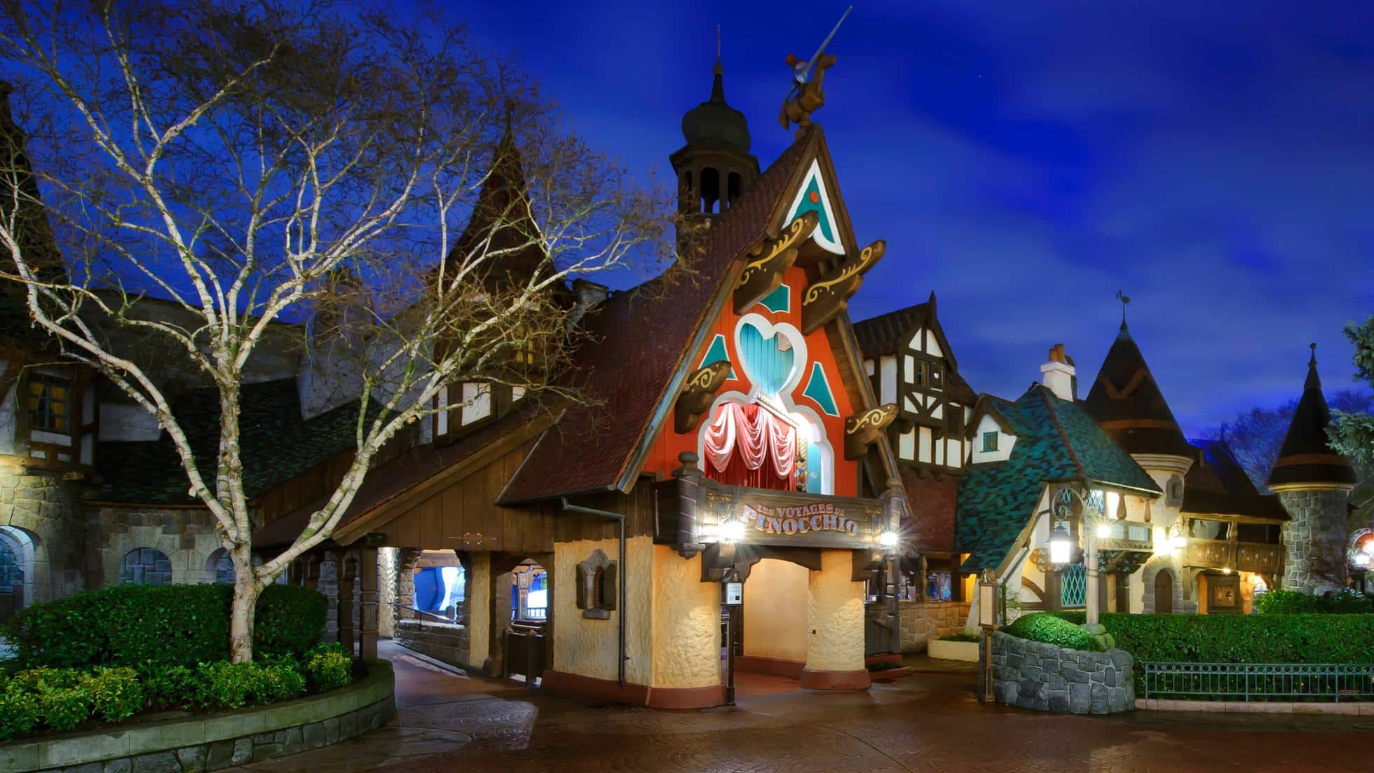 Façade de l'attraction Les Voyages de Pinocchio à Fantasyland, bâtiment de style village européen avec Pinocchio et Jiminy Cricket en décoration