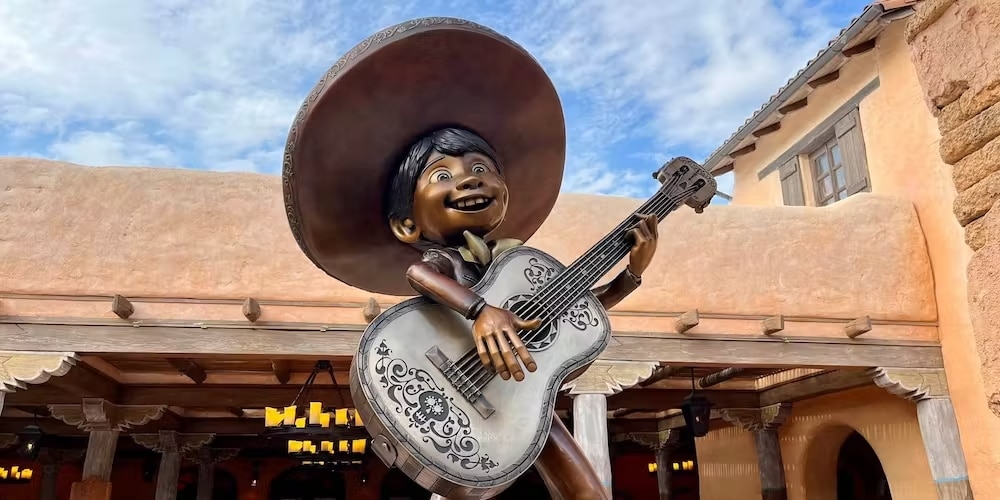Entrée du restaurant Casa de Coco Restaurante de Familia en Frontierland, statue de Miguel jouant de la guitare entourée de papel picados colorés
